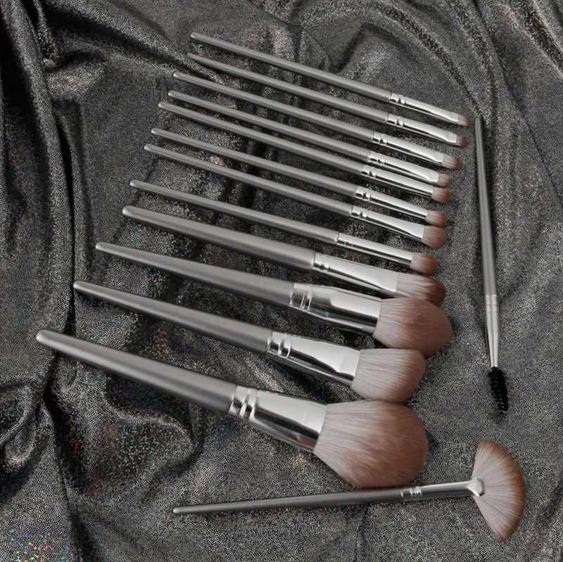 Set di pennelli per trucco su tessuto argentato lucido. Varie forme con manici argentati.