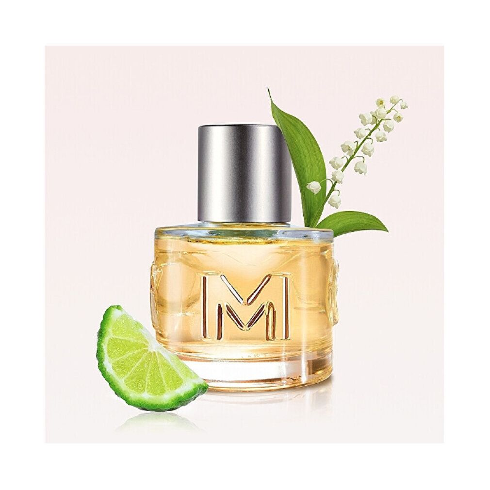 Flacone di profumo MEXX Woman con limone e fiori. Bottiglia cilindrica in vetro con tappo argentato.
