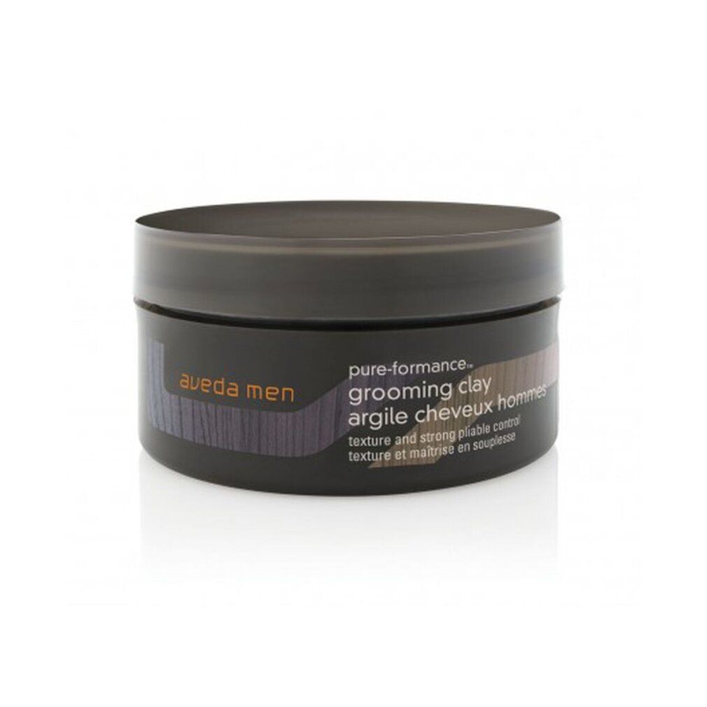 Vaso rotondo marrone scuro con testo. Scritta: Aveda Men, pure-formance, grooming clay, argile cheveux hommes. Vista laterale.