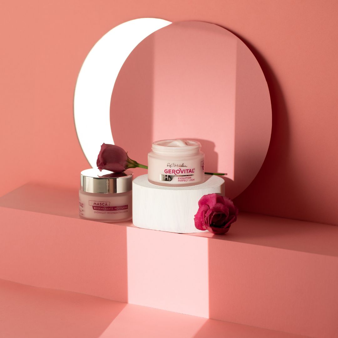 Due vasetti di crema su una piattaforma bianca, circondati da decorazioni rosa. Scritta: Gerovital H3 Evolution Perfect Look. Masca Regeneranta.