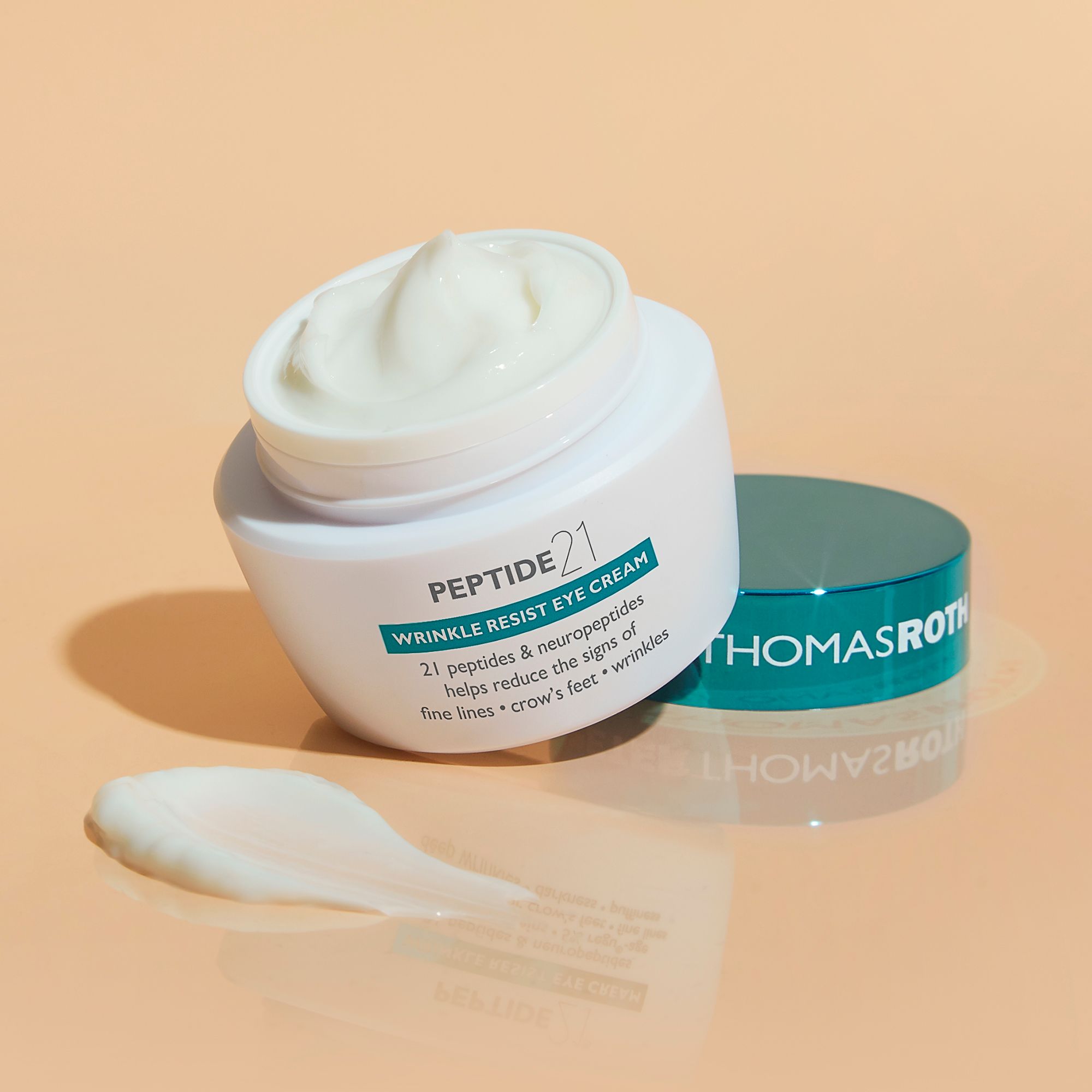 Peter Thomas Roth Peptide 21® Wrinkle Resist Eye Cream. Vasetto aperto, crema e coperchio. Macchia di crema accanto.
