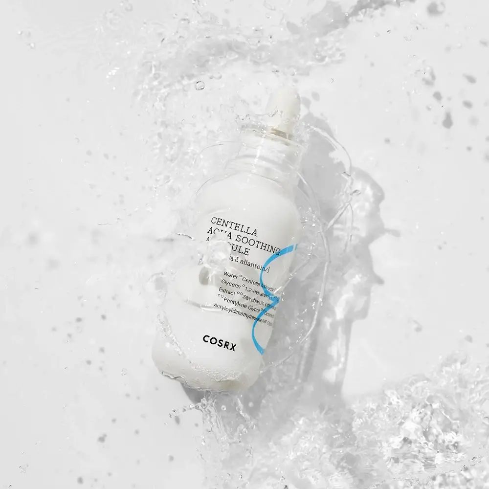 Flacone bianco con etichetta blu nell'acqua. Scritta: Centella Aqua Soothing Ampoule. Marchio: COSRX.