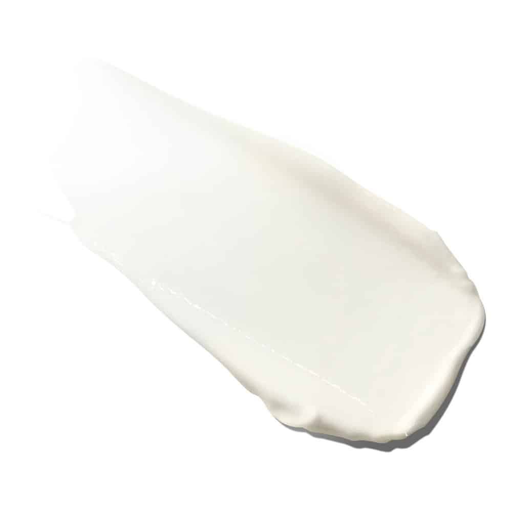 Macchia di crema bianca su sfondo bianco. La consistenza è liscia e cremosa.