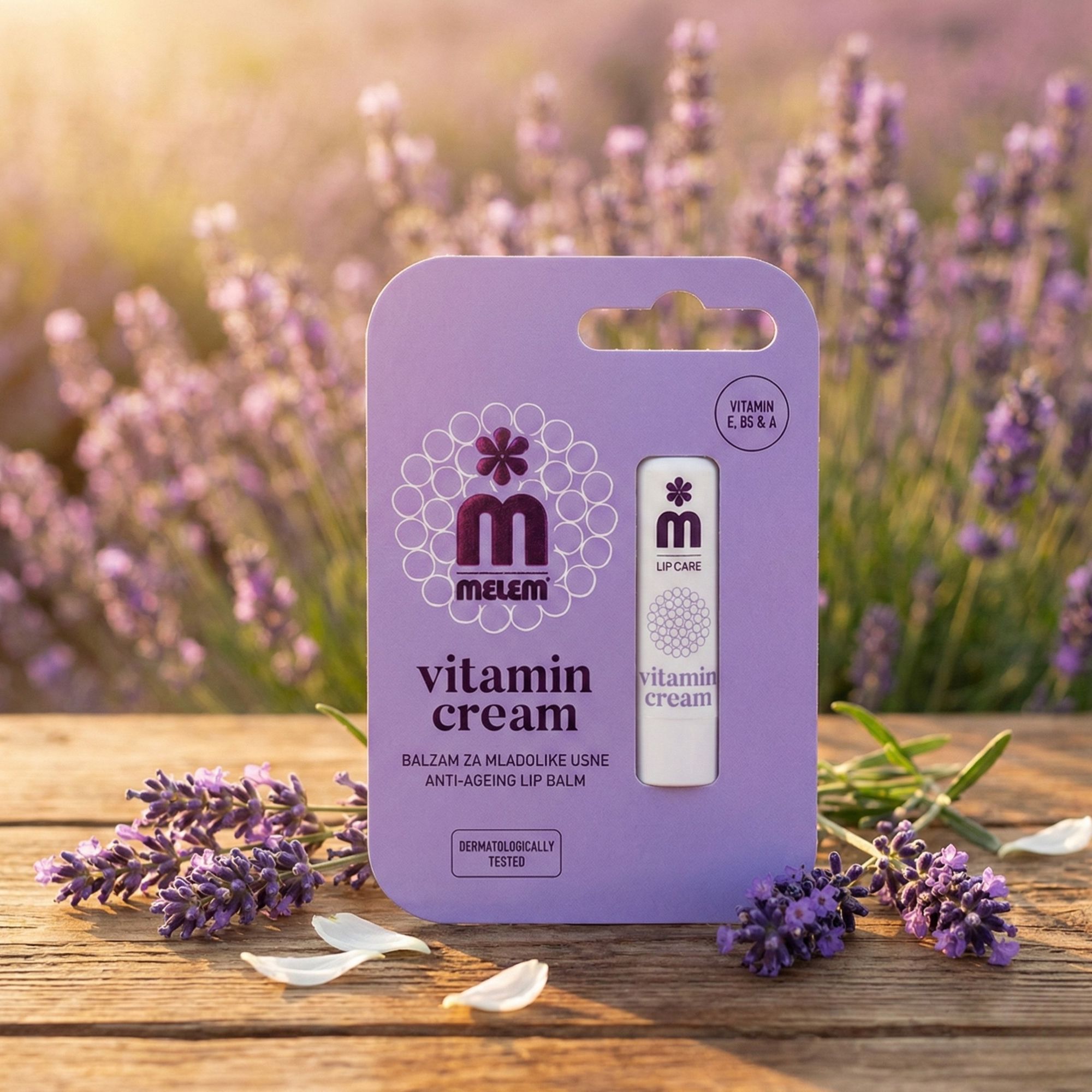 Balsamo per labbra in confezione lilla. Scritta: MELEM, Vitamin Cream, Anti-Aging Lip Balm. Sfondo: fiori di lavanda e legno.