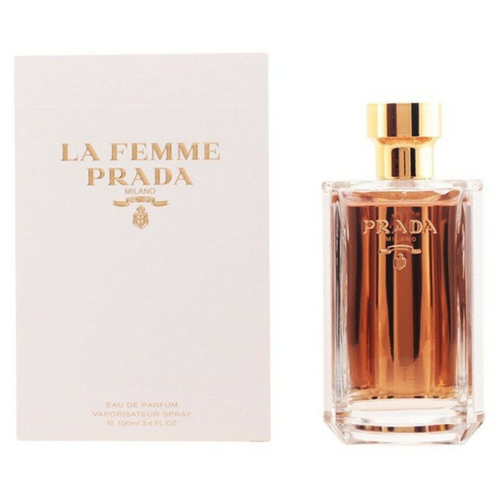 Flacone di profumo accanto a confezione bianca. Sulla confezione 'La Femme Prada'. Flacone con tappo dorato.