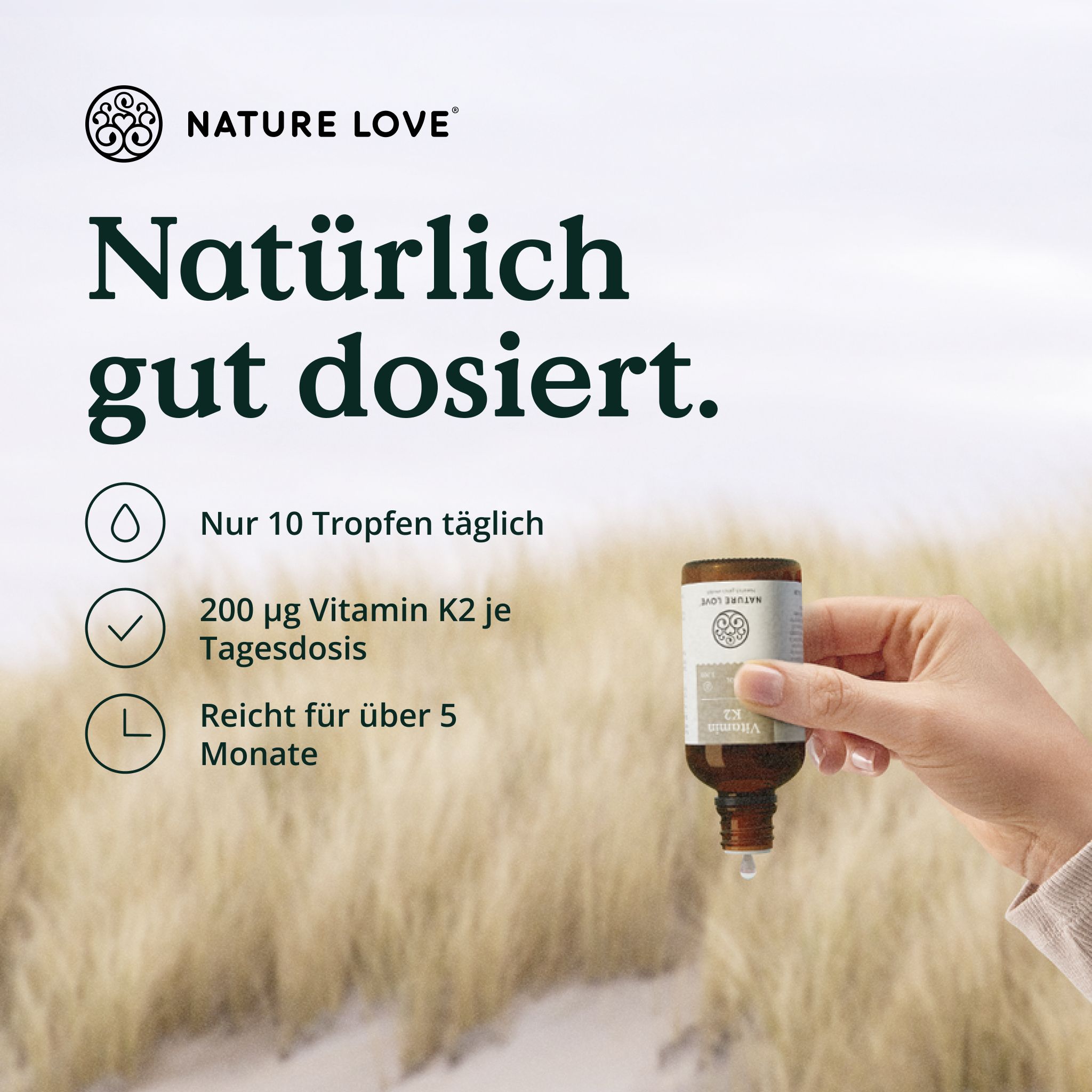 Mano che tiene un flacone di Vitamina K2 di Nature Love, una goccia cade.