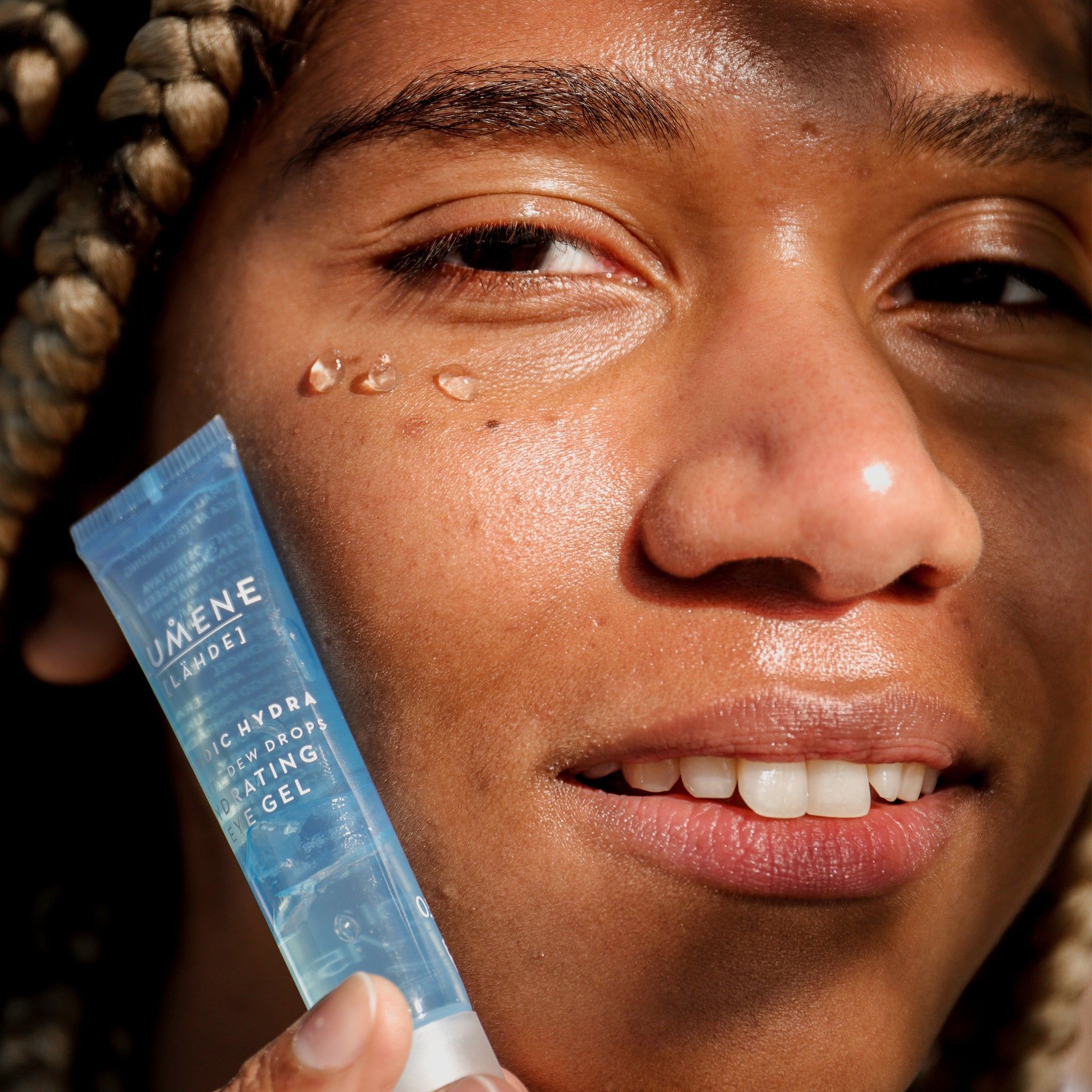Persona tiene il tubo davanti al viso. Scritta: Lumene [LAHDE] Nordic Hydra Purity Dew Drops Hydrating Eye Gel. Gocce di gel sulla pelle.