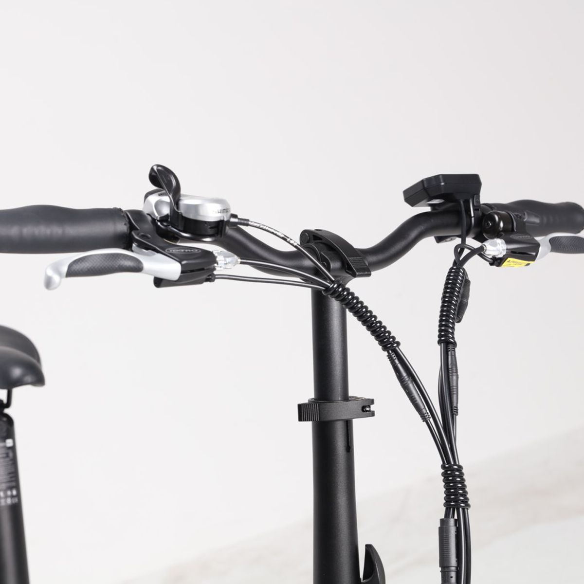 Manubrio della e-bike. Colore nero, leve freno, campanello e comandi. Cavi.