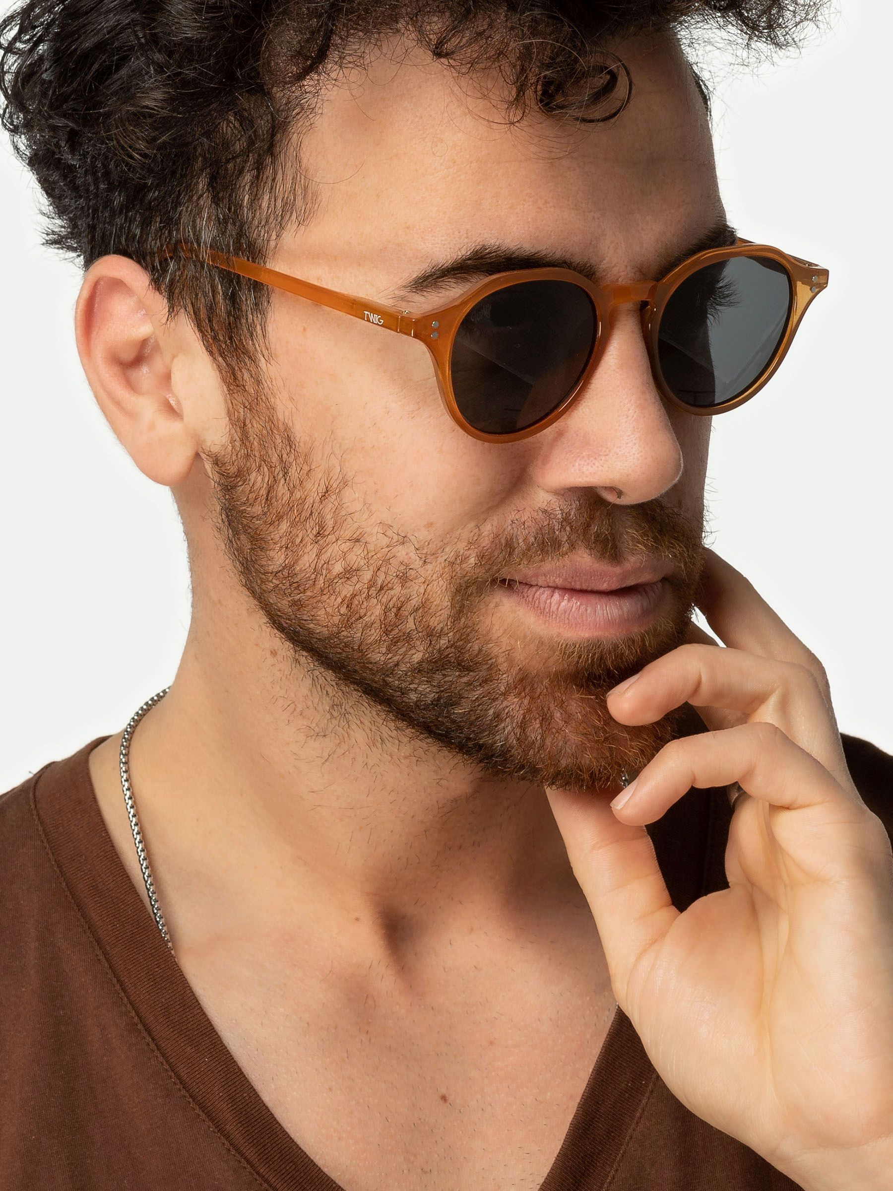 Uomo con occhiali da sole Twig Honey Orange. Montatura marrone, lenti scure.