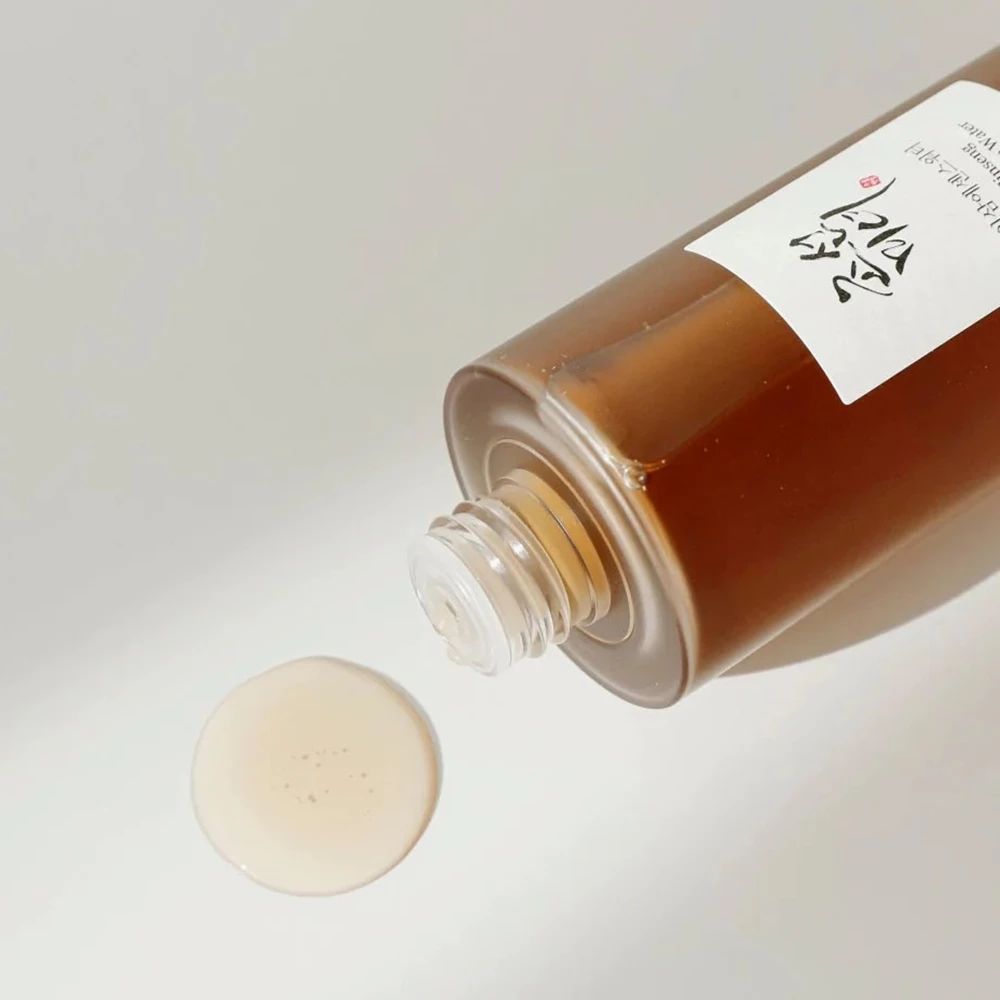 Liquido che gocciola da un flacone su una superficie. Pozzanghera di liquido rotonda. Flacone con etichetta.