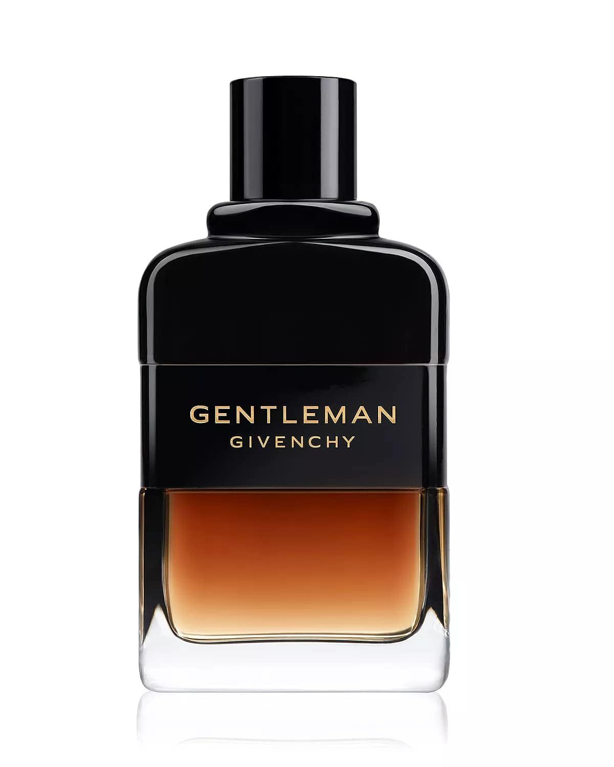 Flacone scuro con tappo nero. Scritta dorata "GENTLEMAN GIVENCHY". Liquido sfumato. Sfondo con iris e legno.