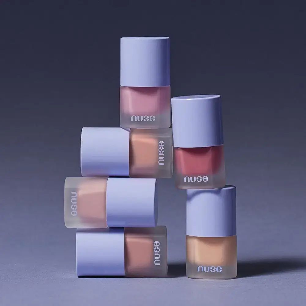 Sei flaconi di fard, tappi viola, contenuto rosa, impilati. Testo: nuse.