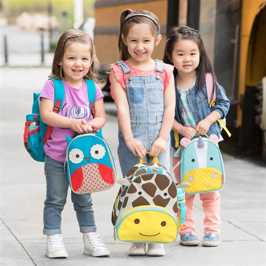 Tre bambini con borse termiche. Gufo, giraffa e unicorno. In piedi davanti a un autobus. Diversi design e colori.