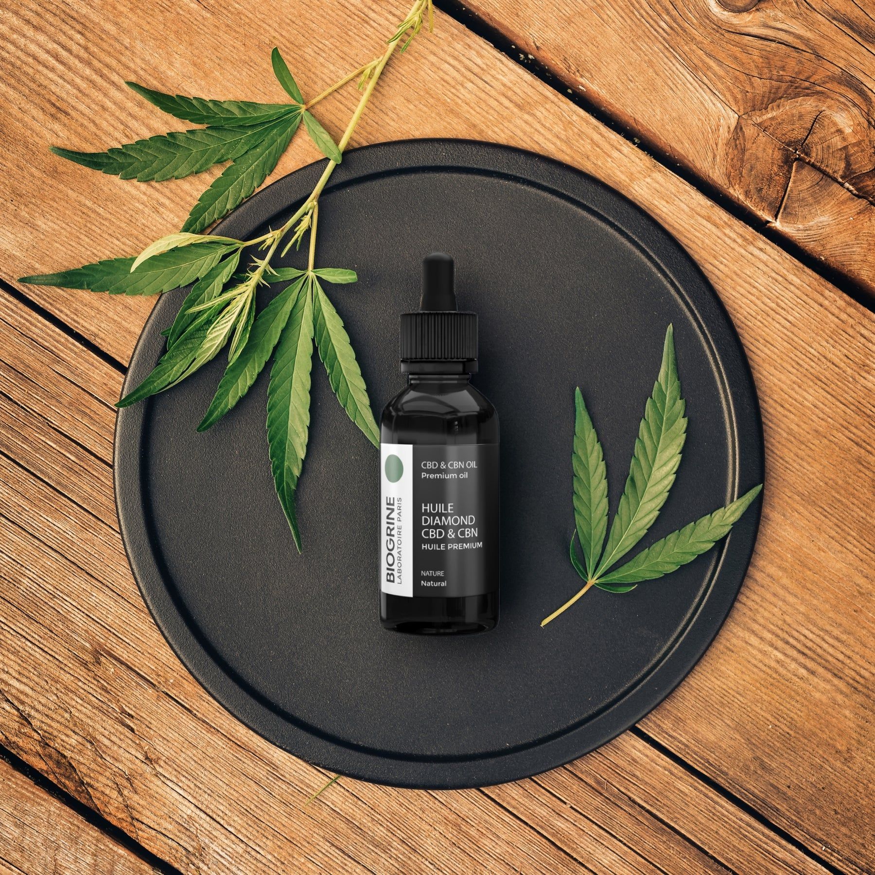 Piatto nero con flacone di olio CBD & CBN e piante di cannabis. Sfondo in legno.