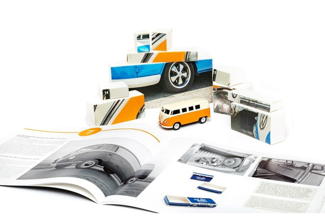 Elementi del calendario dell'Avvento e modello VW Bulli. Parti da assemblare. Libro aperto con immagini e testi.