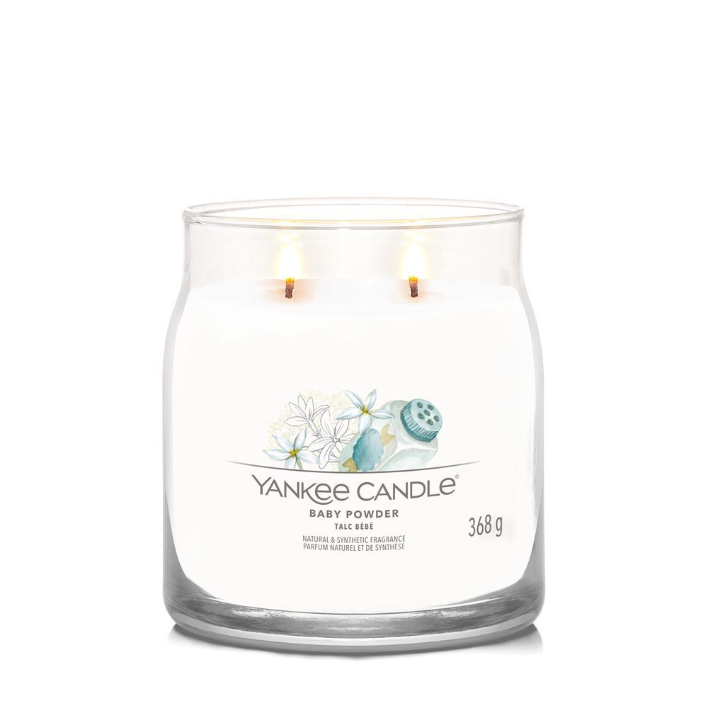 Vaso di vetro con due stoppini accesi. Etichetta con fiori e testo: Yankee Candle Baby Powder. Peso: 368 g.