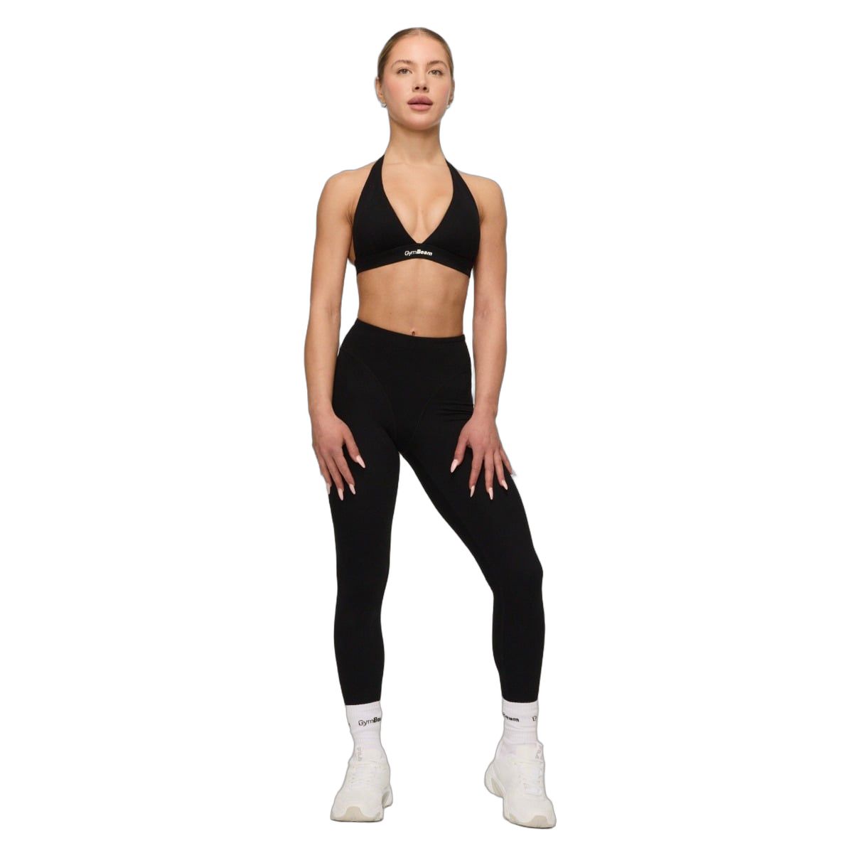 Donna con reggiseno sportivo nero, leggings e calzini bianchi.