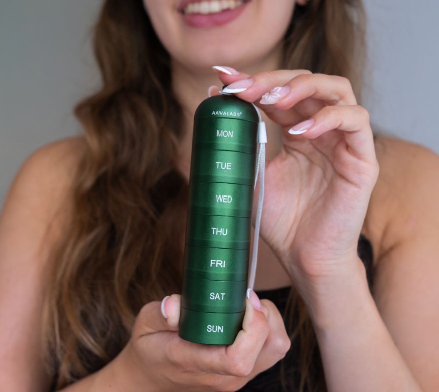 Una donna tiene un portapillole verde a 7 scomparti per i giorni della settimana.