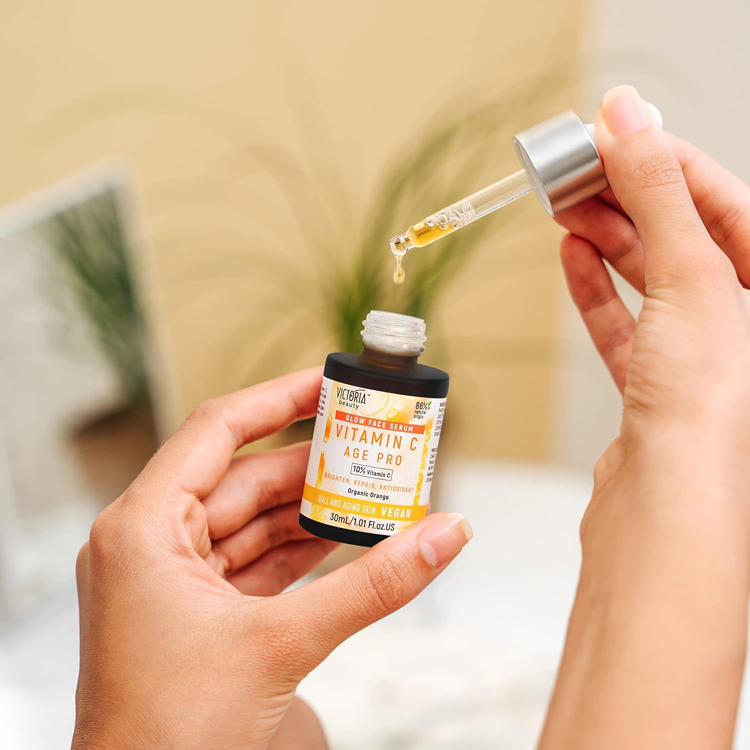 Flacone di siero con contagocce. Gocce che cadono nel flacone. Scritta: Vitamin C Age Pro.