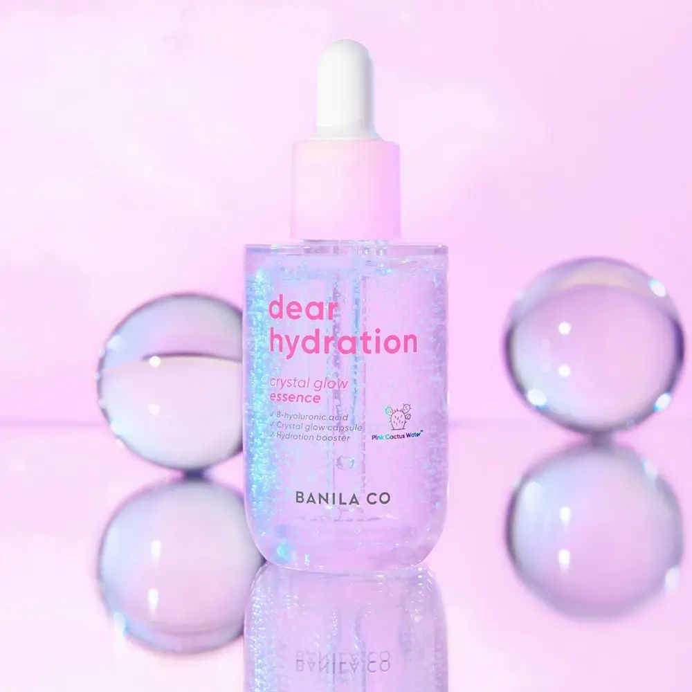 BANILA CO Dear Hydration Crystal Glow Essence. Flacone rosa con tappo e pipetta bianchi. Sfere di vetro.