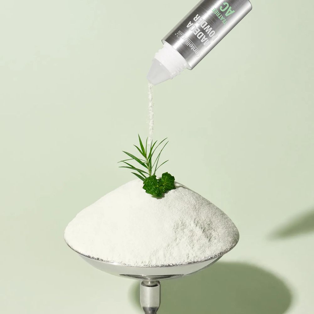 Flacone Centellian24 Madeca Powder TeaTree AC sopra un mucchio di polvere.