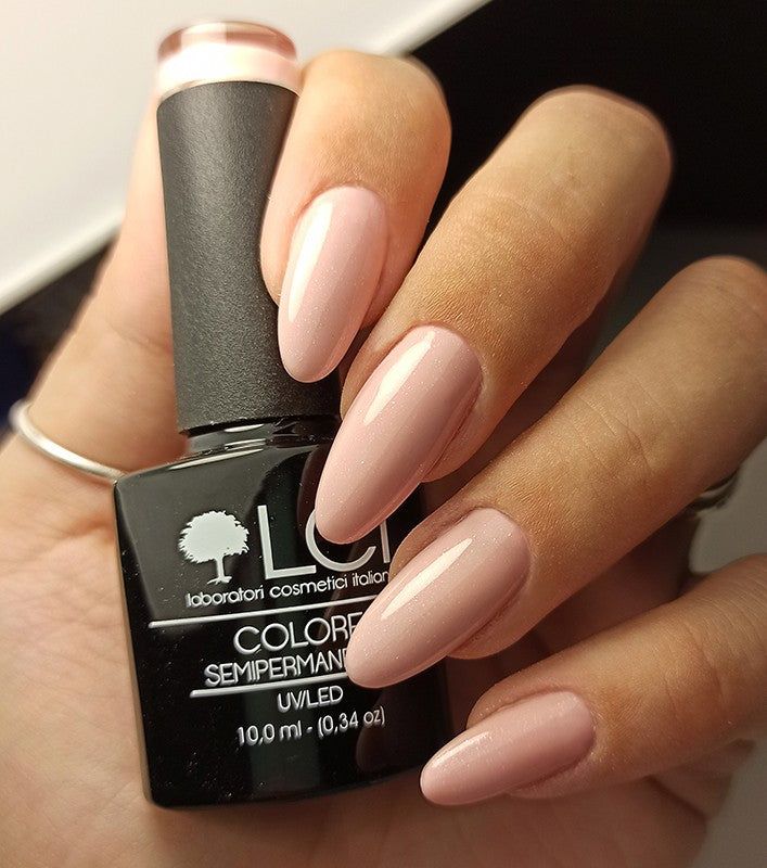 Mano con unghie smaltate e flacone di smalto. Scritta: LCI, Colore Semipermanente, UVLED.