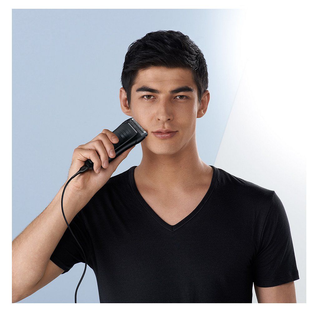 Uomo che usa un rasoio elettrico Braun Series 1 per radersi. Il dispositivo è collegato al cavo di ricarica.