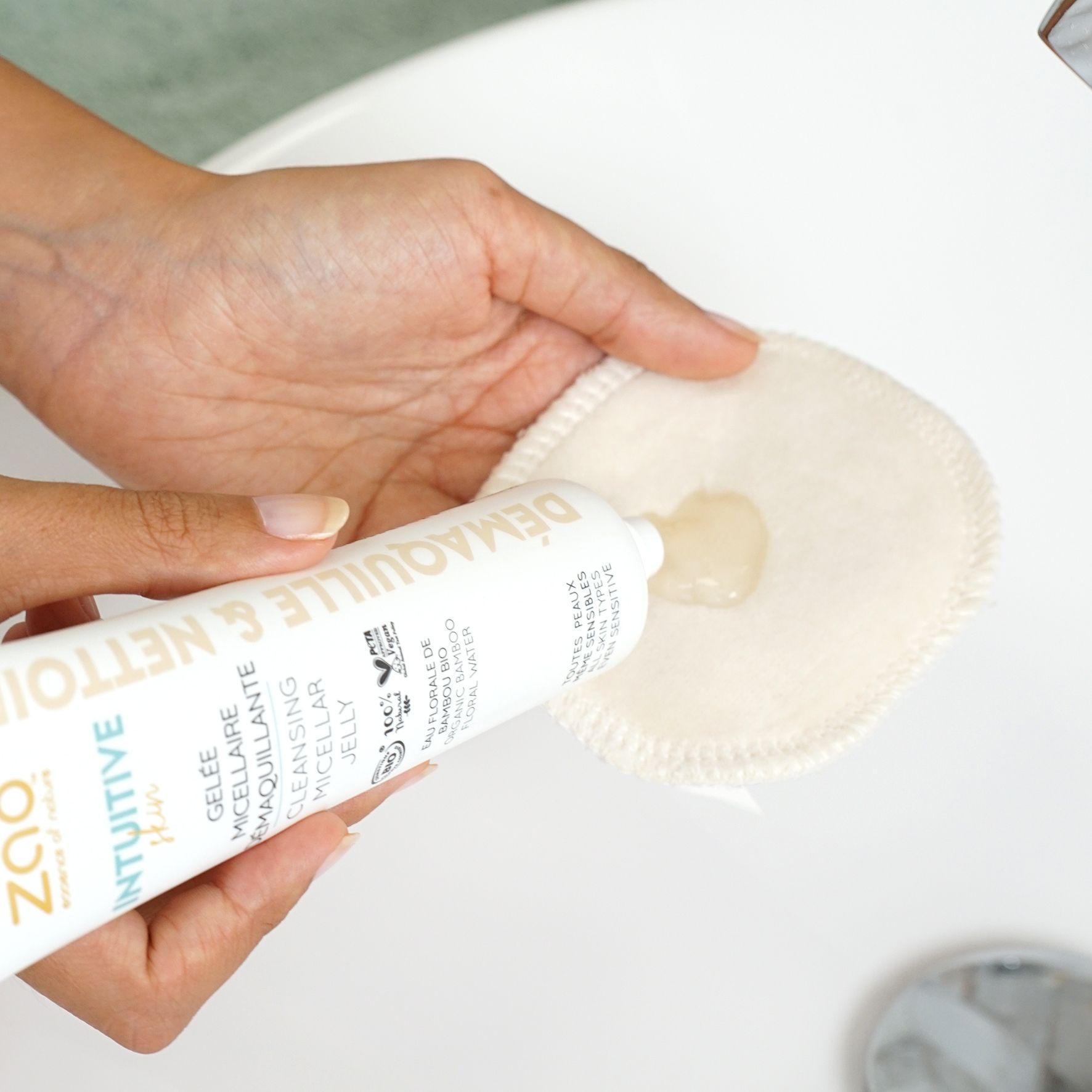 Pad rotondo in cotone con gel. Una mano tiene il pad, l'altra preme il gel da un tubetto.