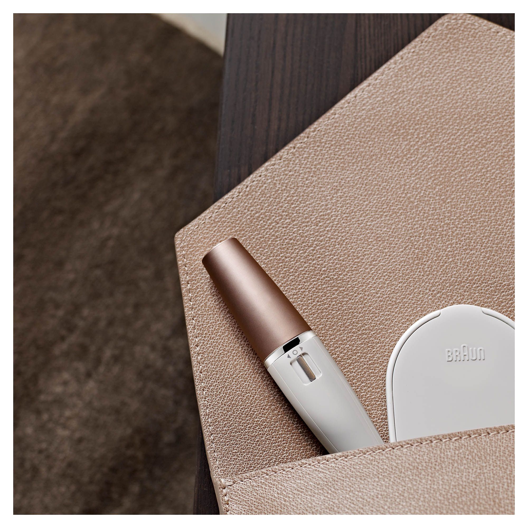 Epilatore e spazzola per la pulizia del viso bianchi, accessori in un beauty case beige.