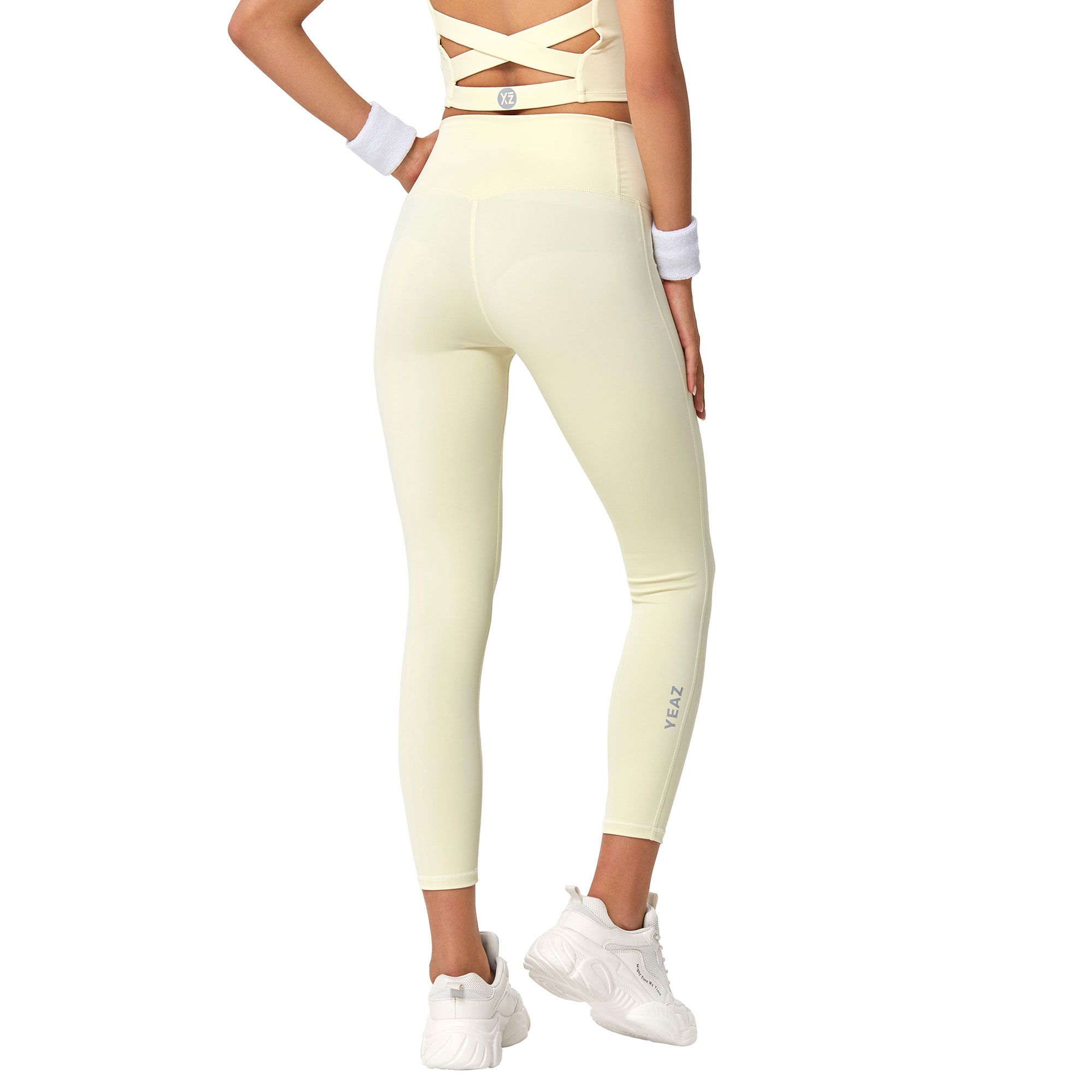 Leggings giallo chiaro a vita alta con reggiseno sportivo con spalline incrociate. Nome del marchio discreto sulla gamba.