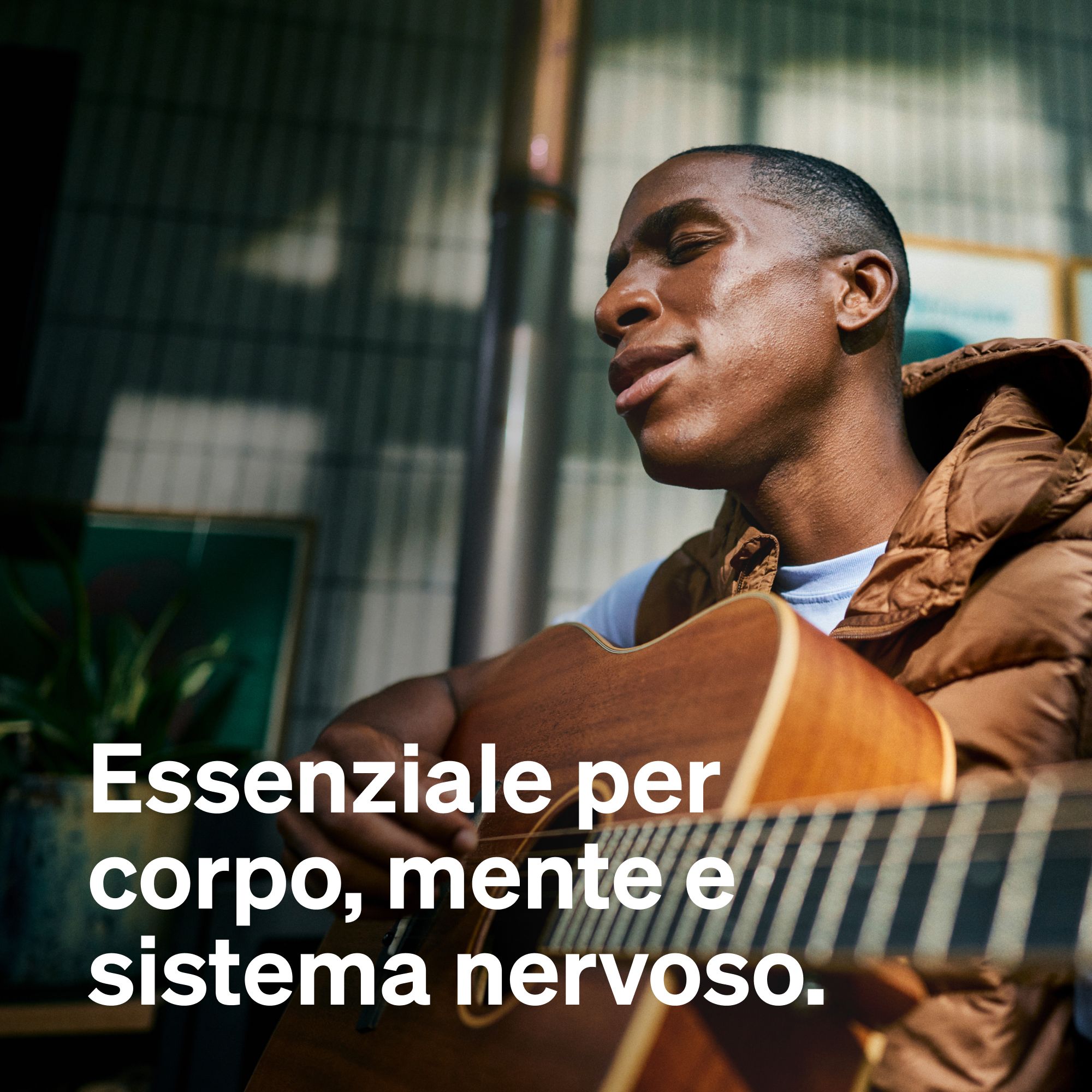 Uomo che suona la chitarra e canta, con testo 'Essenziale per corpo, mente e sistema nervoso'.
