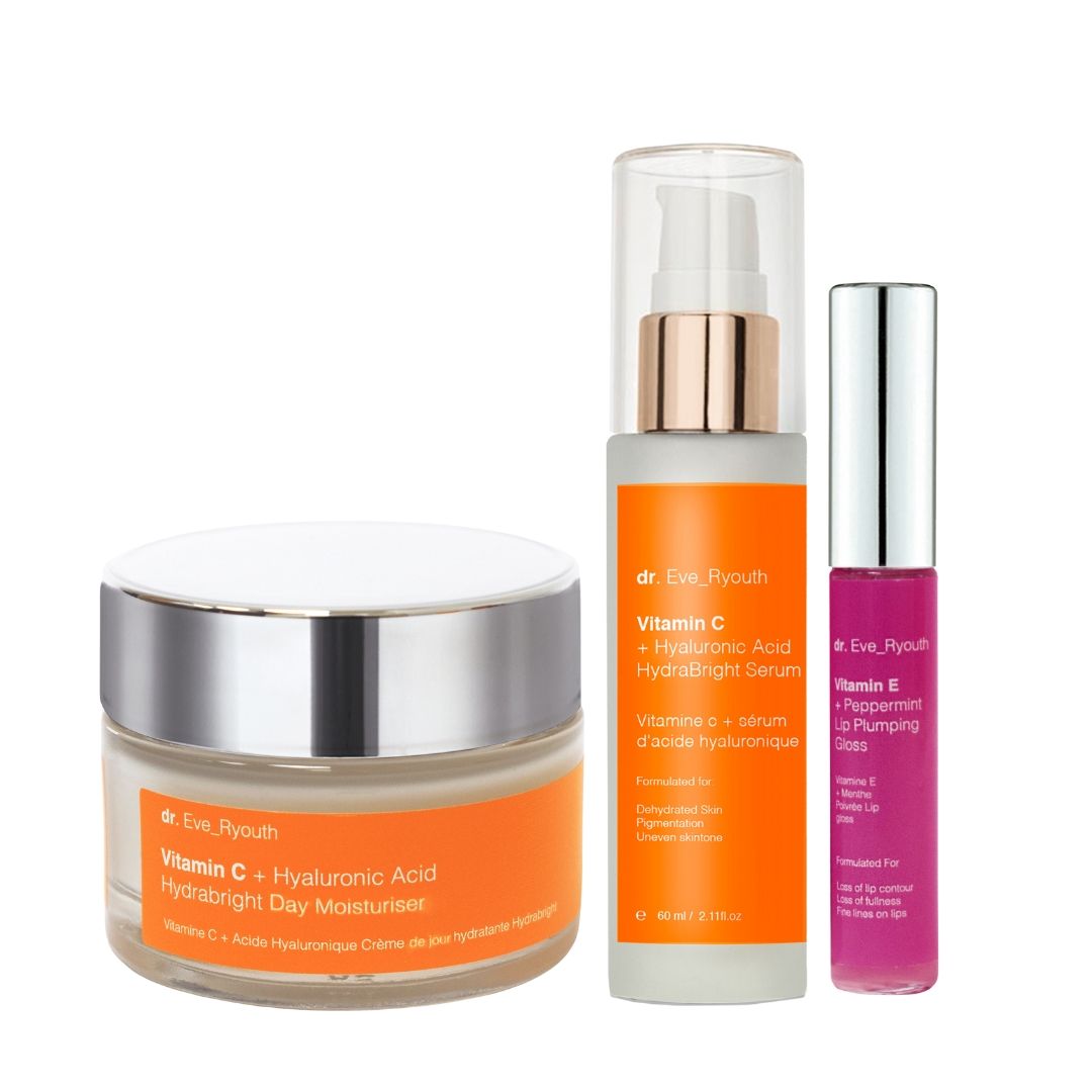 Tre prodotti cosmetici: crema, siero e lucidalabbra. Vasi di crema e siero con etichette arancioni. Lucidalabbra rosa.