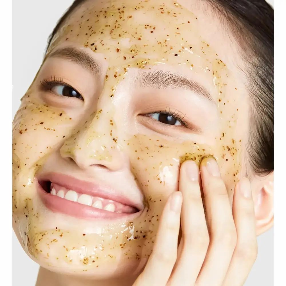 Viso di donna con maschera. La maschera è giallastra e contiene piccole particelle. La donna sorride.