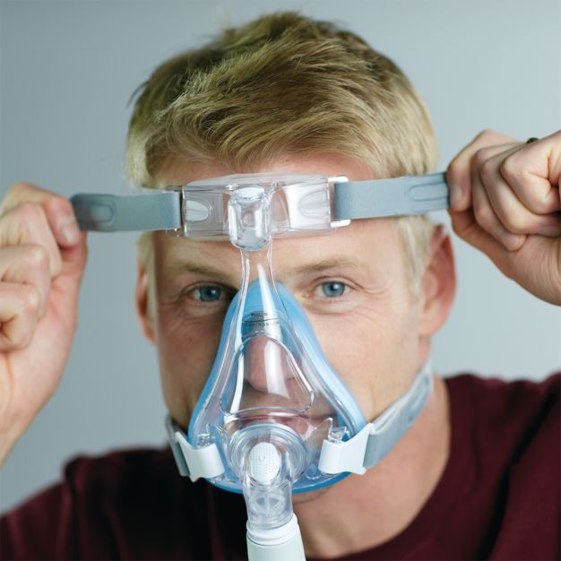 Uomo con maschera CPAP Philips Amara SE Gel Full: regolazione del copricapo.
