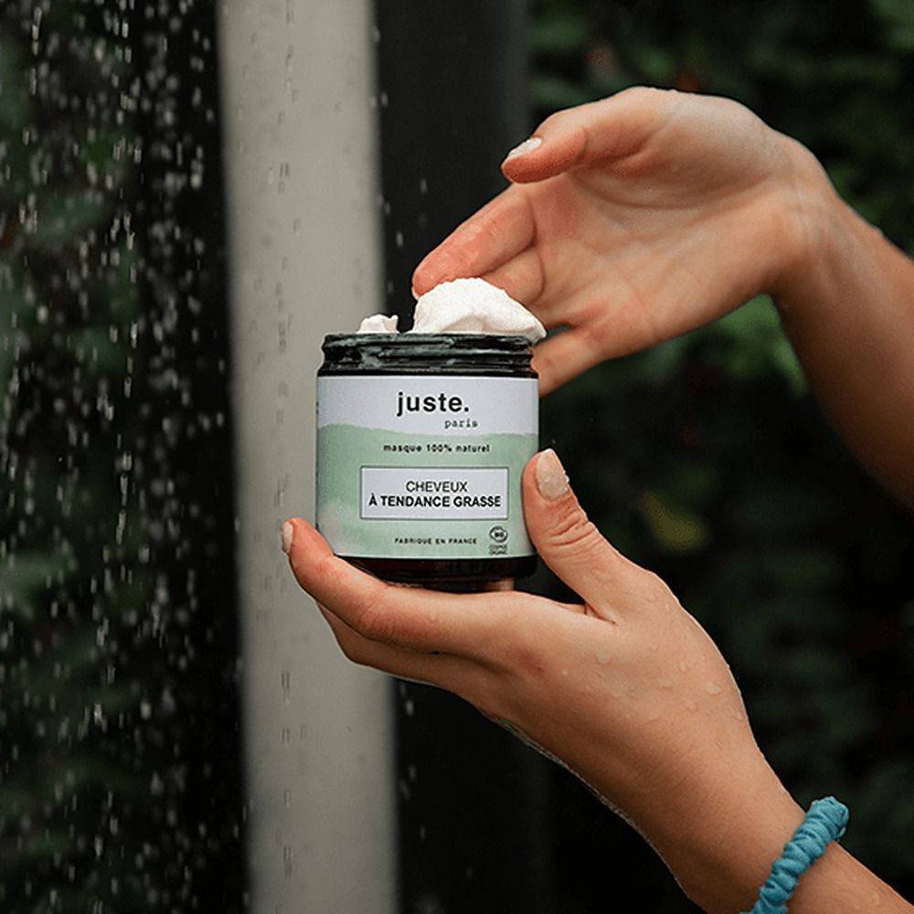 Mani che tengono un barattolo di crema bianca. Gocce d'acqua sono visibili sullo sfondo.