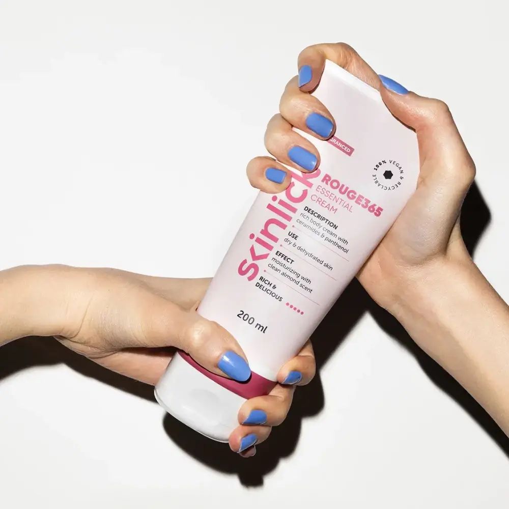 Tubo bianco-rosa SKINLICK Rouge365 Essential Cream. Mani che tengono il tubo. 200 ml. Sigillo vegano.
