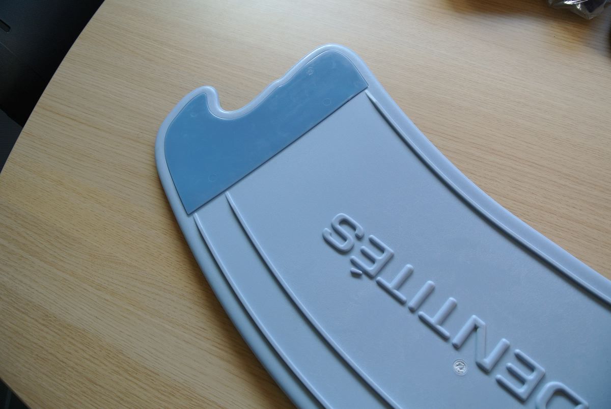 Primo piano di una tavola di trasferimento blu, forma arrotondata, due intagli. Scritta: IDENTITÉS.