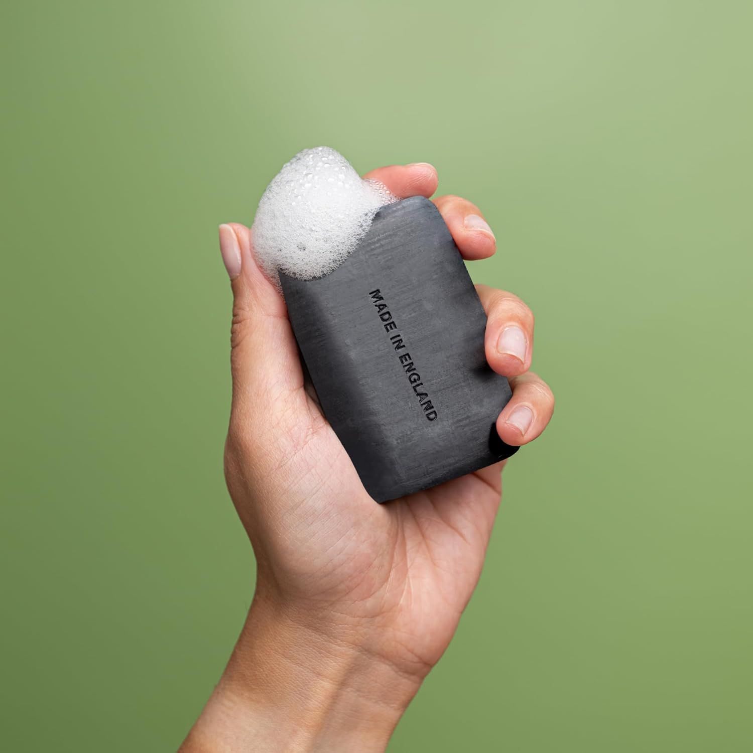 Mano che tiene sapone nero con schiuma. Scritta: Made in England.