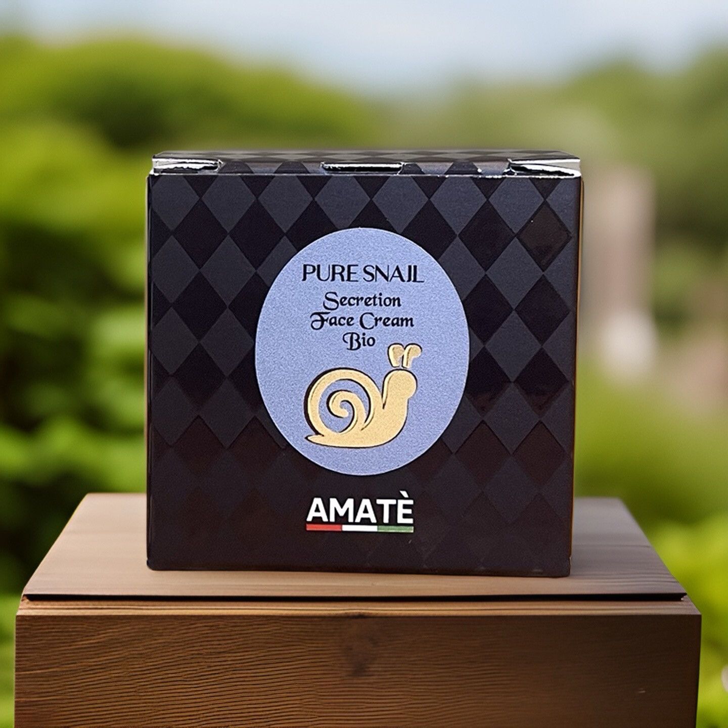 Scatola quadrata con scritta: Pure Snail Secretion Face Cream Bio. Logo: lumaca dorata. Marchio: Amatè. Sfondo: verde.