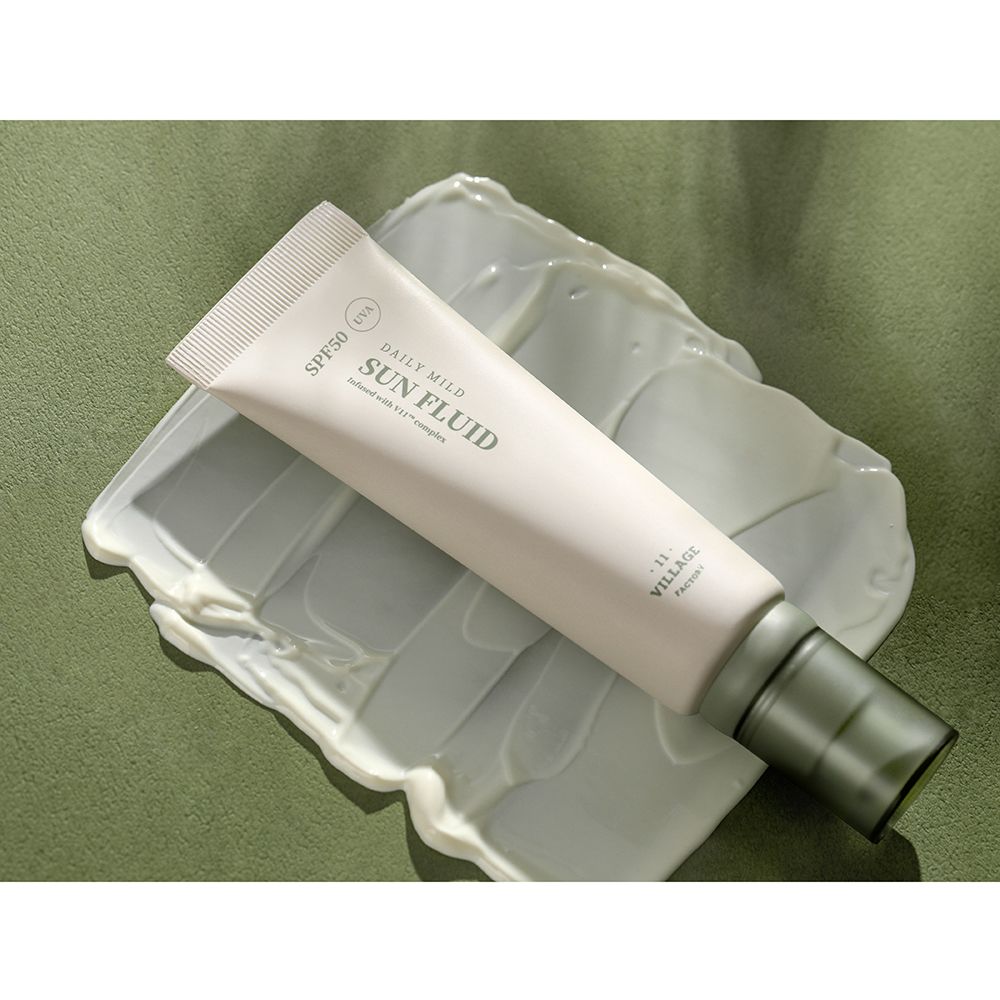 Tubo 'DAILY MILD SUN FLUID SPF50' su crema. Sfondo verde.