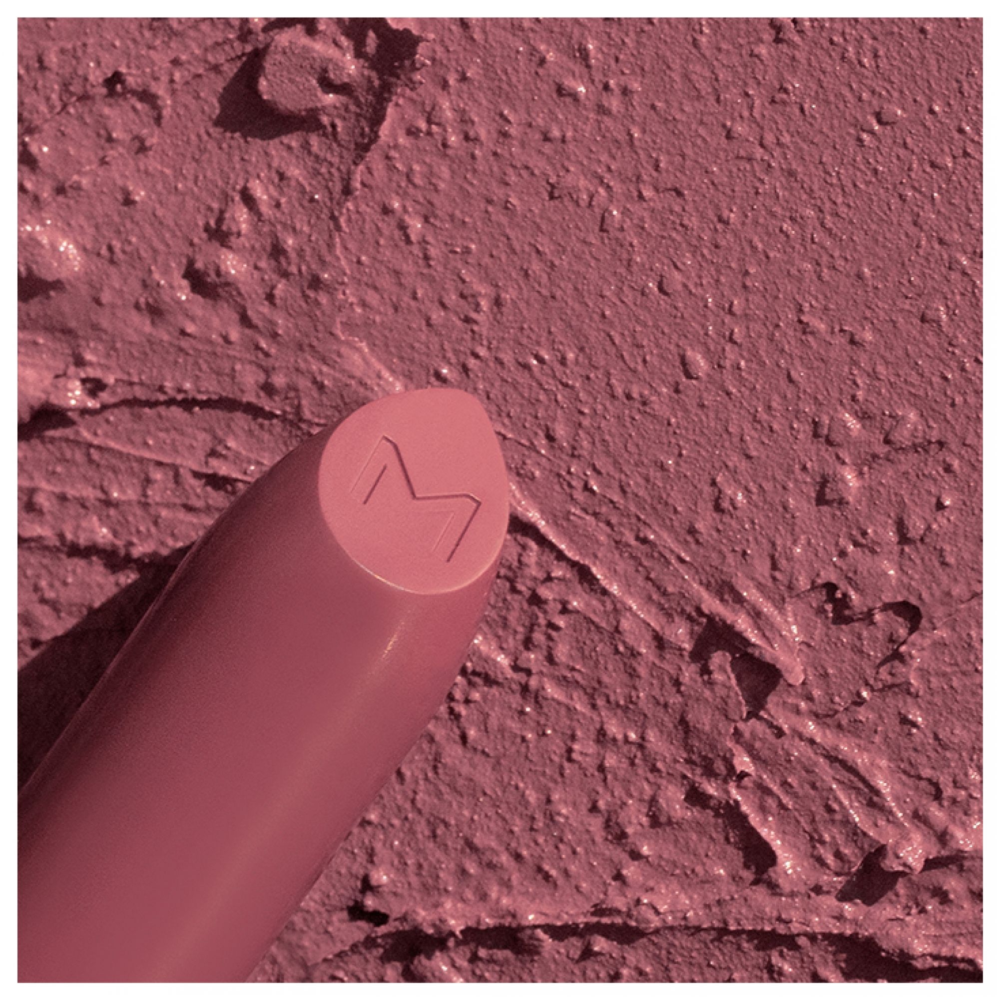 Rossetto opaco con logo M sulla punta, applicato su una texture.