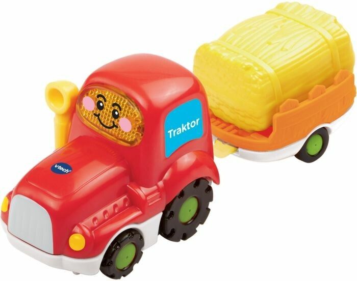 Trattore rosso con rimorchio. Rimorchio con balla di fieno gialla. Scritta: Traktor.