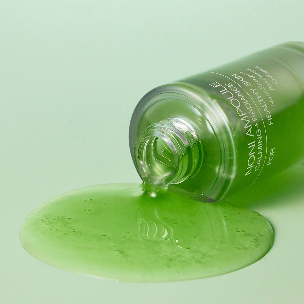 Liquido verde versato da una fiala Celimax Noni Energy rovesciata.