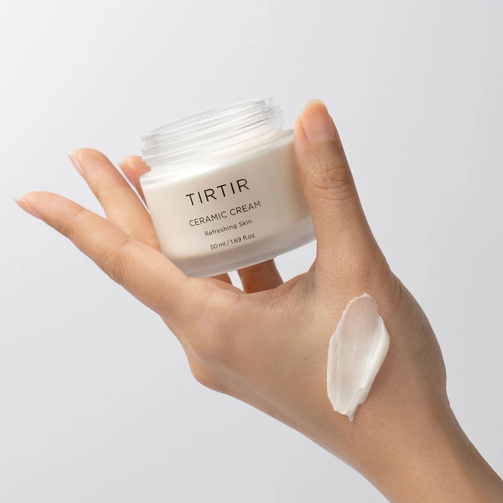 Mano che tiene un vasetto aperto di Tir Tir Ceramic Cream e una noce di crema. Scritta: Ceramic Cream, Refreshing Skin, 50 ml.