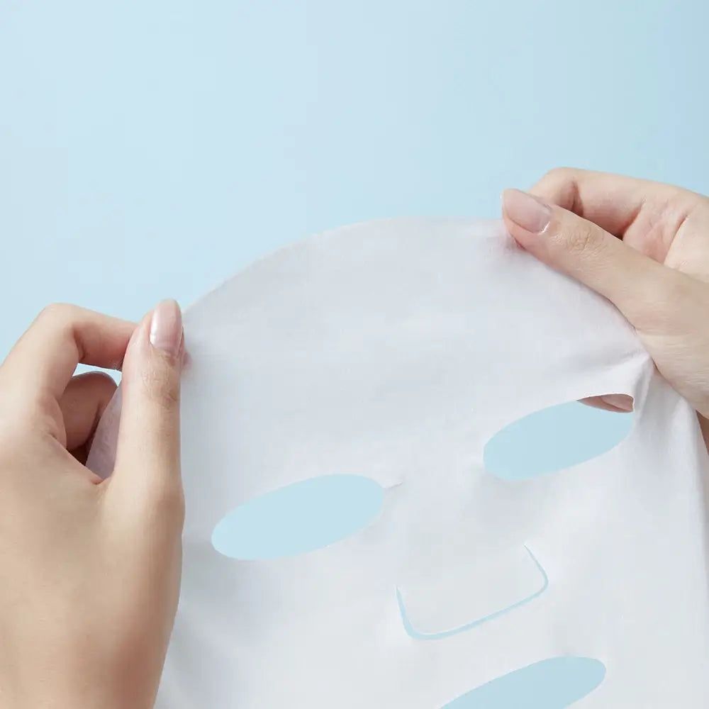 Maschera viso bianca con fori. Mani che tengono la maschera. Sfondo azzurro.
