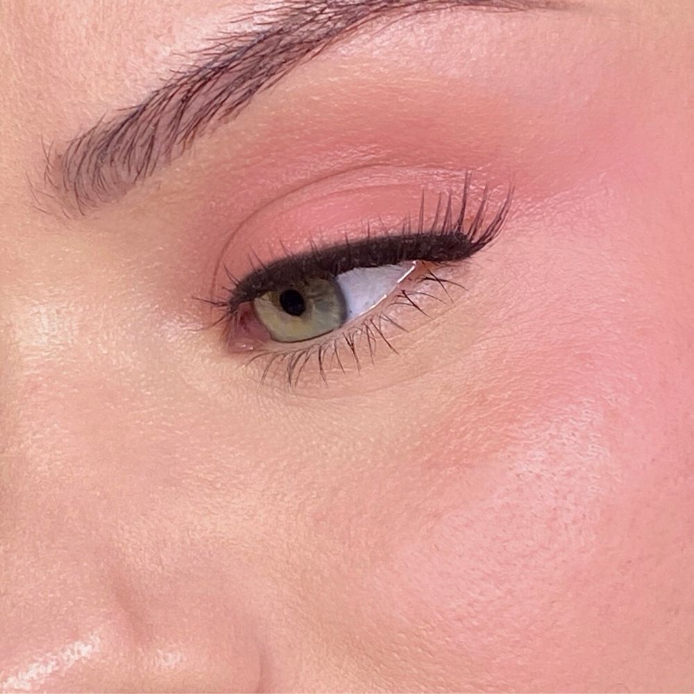 Primo piano di un viso con trucco rosa su occhi e guance. Occhio verde, eyeliner nero.