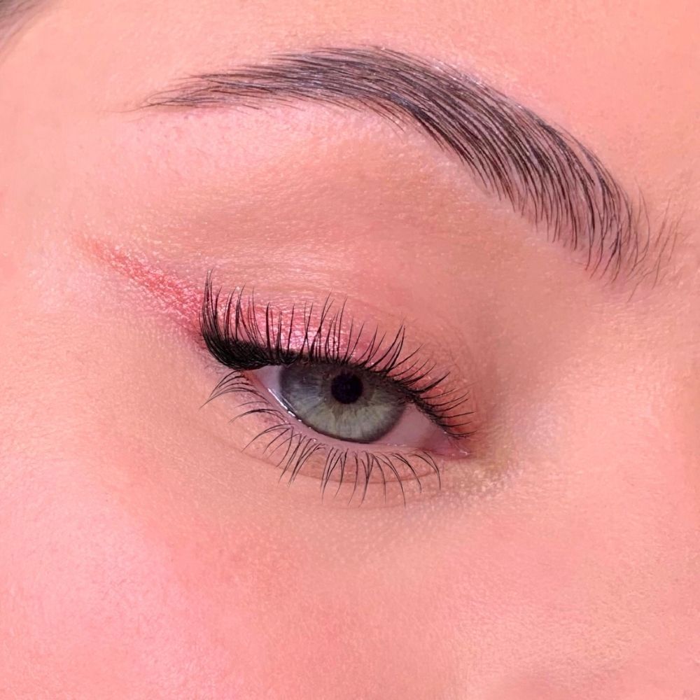 Occhio con eyeliner e ombretto rosa. Lunghe ciglia, sopracciglio. Tono della pelle.