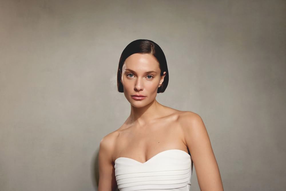 Ritratto di donna con capelli scuri e top bianco. Sguardo verso la fotocamera.