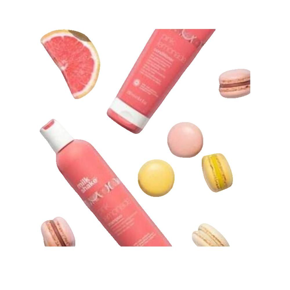 Flacone e tubo rosa con nomi dei prodotti. Marchio Milk Shake. Shampoo e balsamo Pink Lemonade. Macarons e pompelmo.