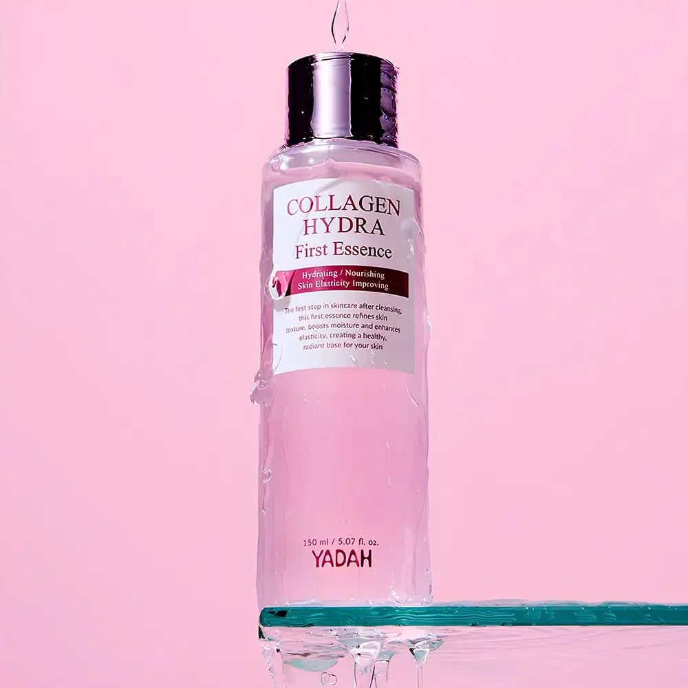 Flacone trasparente con liquido rosa. Scritta: Collagen Hydra First Essence. Gocce che cadono dal flacone.
